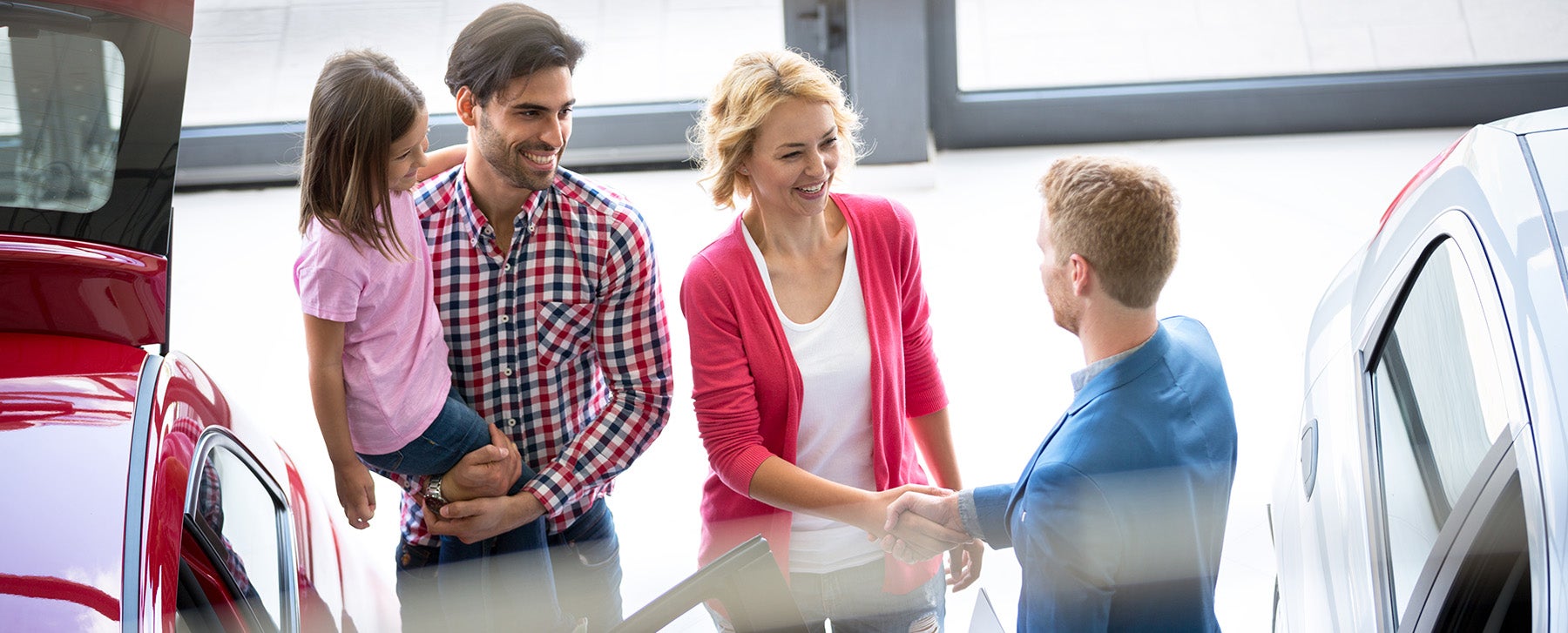 Family shaking hands with car salesman